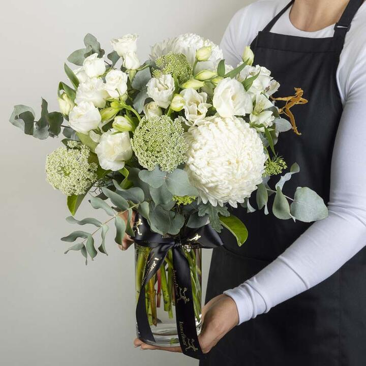 The popular mixed bouquet in a vase includes an assortment of white and cream flowers arranged together...