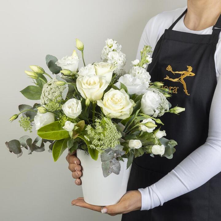 Our mixed floral arrangements in a ceramic vase includes an assortment of white and cream flowers...