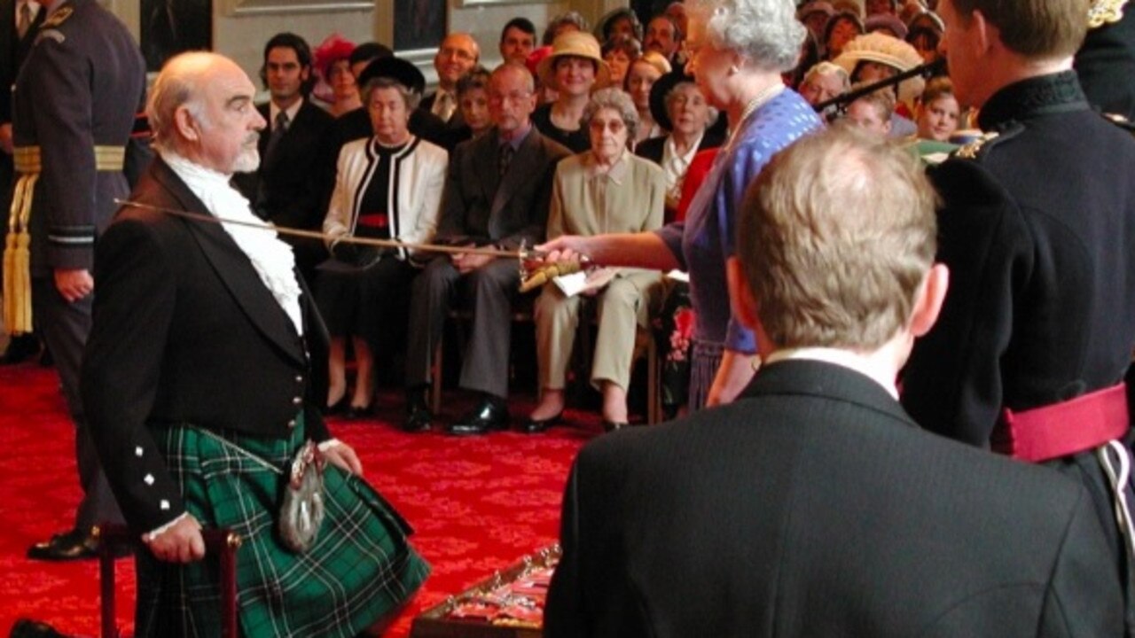 Kneeling as he was knighted by the Queen in 2000