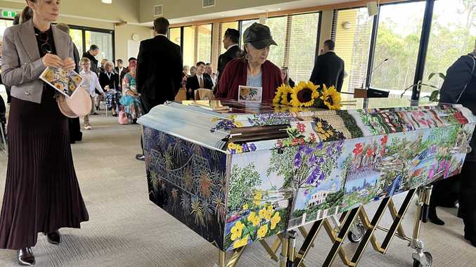  A mourner at the funeral for Red Hill artist and beloved mum and grandmother Kathleen Allam, views the casket covered with pictures of her artwork.
