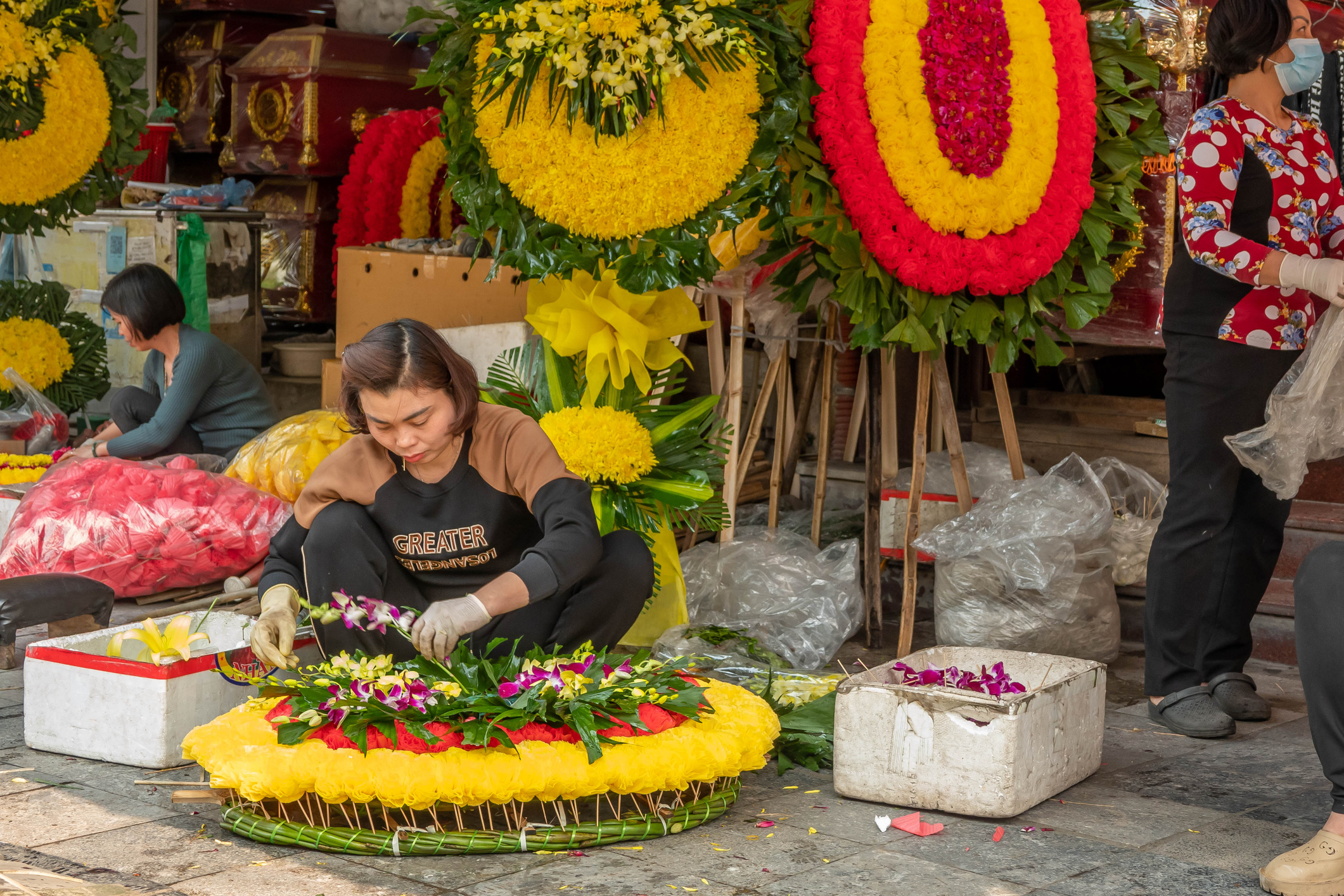 A woman prepares a wreath on the street in Hanoi for an upcoming funeral. Cremation in Bali.