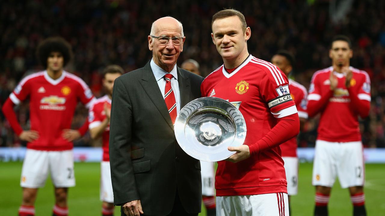 Wayne Rooney (R) of Manchester United is presented a trophy by Sir Bobby Charlton (L). Photo by Clive Brunskill/Getty Images.